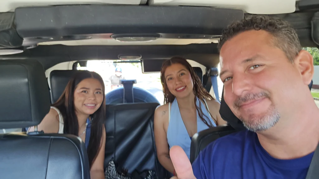 Friendly tour guide taking a selfie with two smiling female guests sitting in the back of a Jeep Wrangler during a fun private tour in Cozumel.