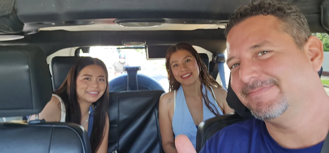 Friendly tour guide taking a selfie with two smiling female guests sitting in the back of a Jeep Wrangler during a fun private tour in Cozumel.