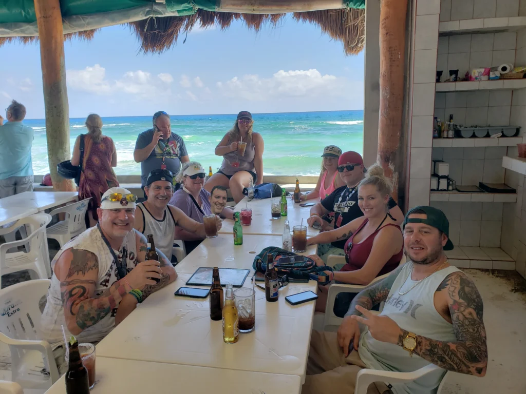 A happy group on their Cozumel tour with lunch, enjoying drinks at a rustic beach bar in Cozumel after a private jeep adventure.