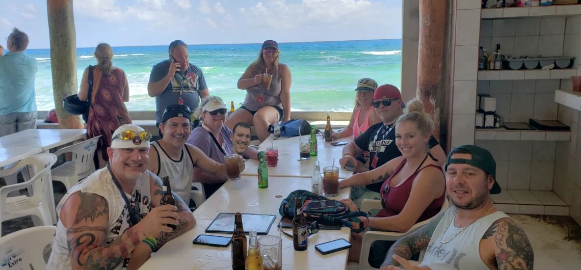 A happy group on their Cozumel tour with lunch, enjoying drinks at a rustic beach bar in Cozumel after a private jeep adventure.