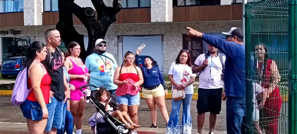 A large family group, including a child in a stroller, attentively listening to their local guide during a private Cozumel family tours